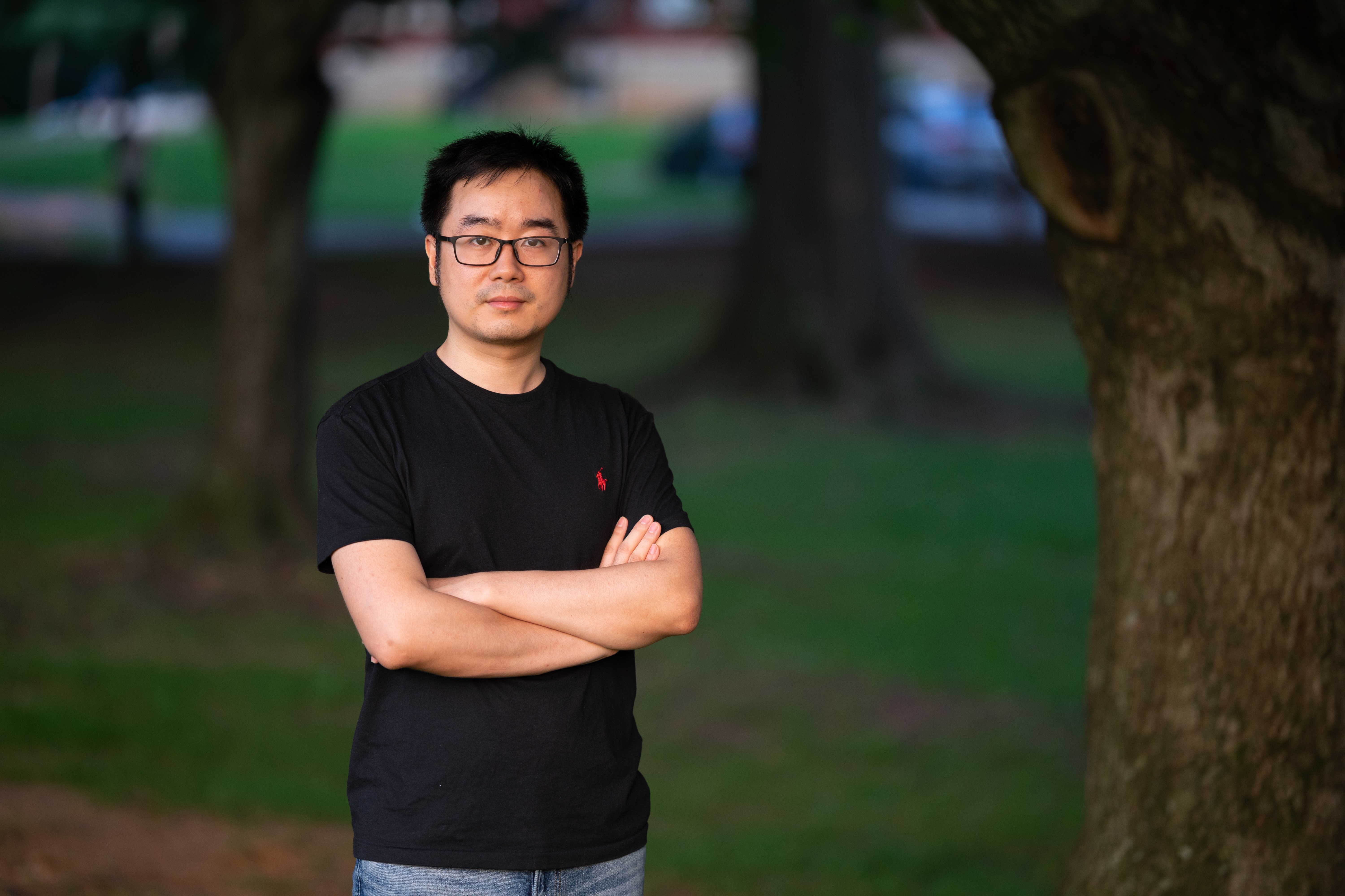 EPSS Assistant professor, Peng Ni standing with arms crossed on a wooded background